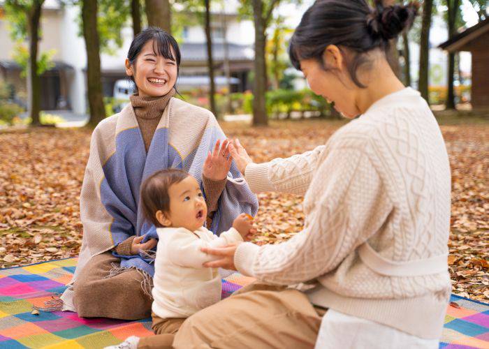 Two women laughing while playing with a young child sat between them.